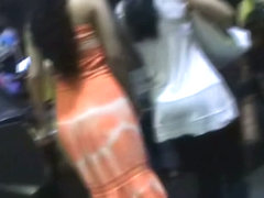 Amateur upskirt video shows a girl in a seductive orange dress.