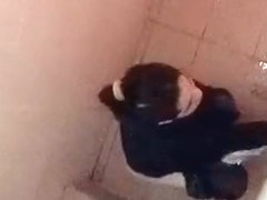 Asian woman spied over the toilet wall taking a pee